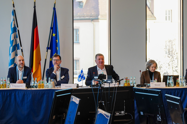 Vier Personen sitzen an einem Konferenztisch bei der Bauministerkonferenz in Würzburg