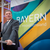 Verkehrsminister Christian Bernreiter steht an einem Rednerpult. Im Hintergrund kann man auf einem Roll-up "Bayern - das Innovationsland" lesen.